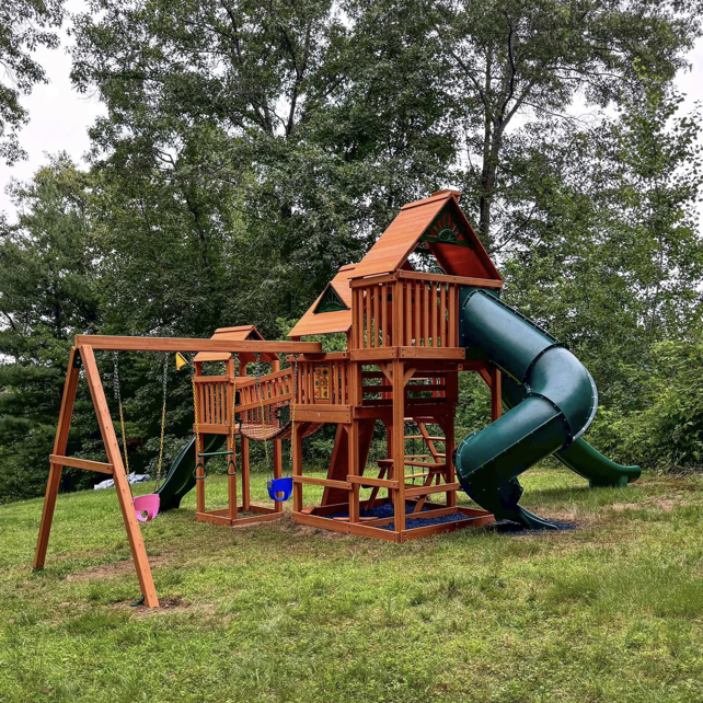 A large wooden playset with slides and swings assembled by Vlad's Handyman Services in Manchester, NH.