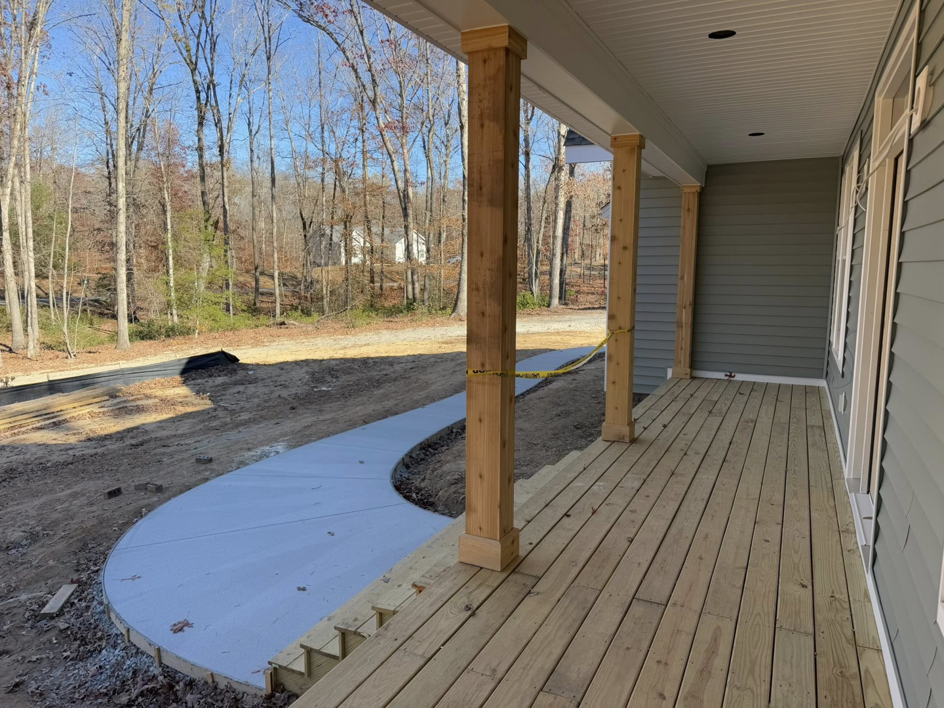 A newly constructed wooden porch with sturdy columns and a curved concrete walkway by River City Builders in Richmond, VA.