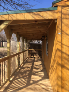 A detailed view of a wooden porch with railing and outdoor lighting fixtures, built by K&K Construction LLC in Enid, OK