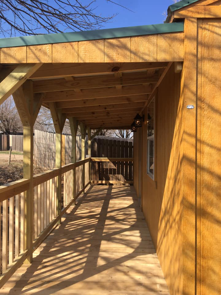 A detailed view of a wooden porch with railing and outdoor lighting fixtures, built by K&K Construction LLC in Enid, OK