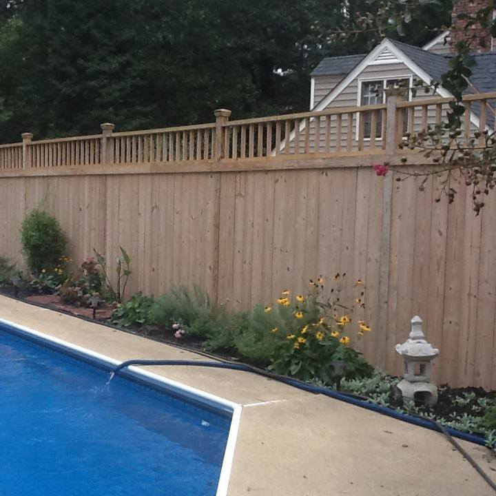 A newly installed wooden privacy fence next to a swimming pool by Fence Me In And Decks Too in Glen Allen, VA.