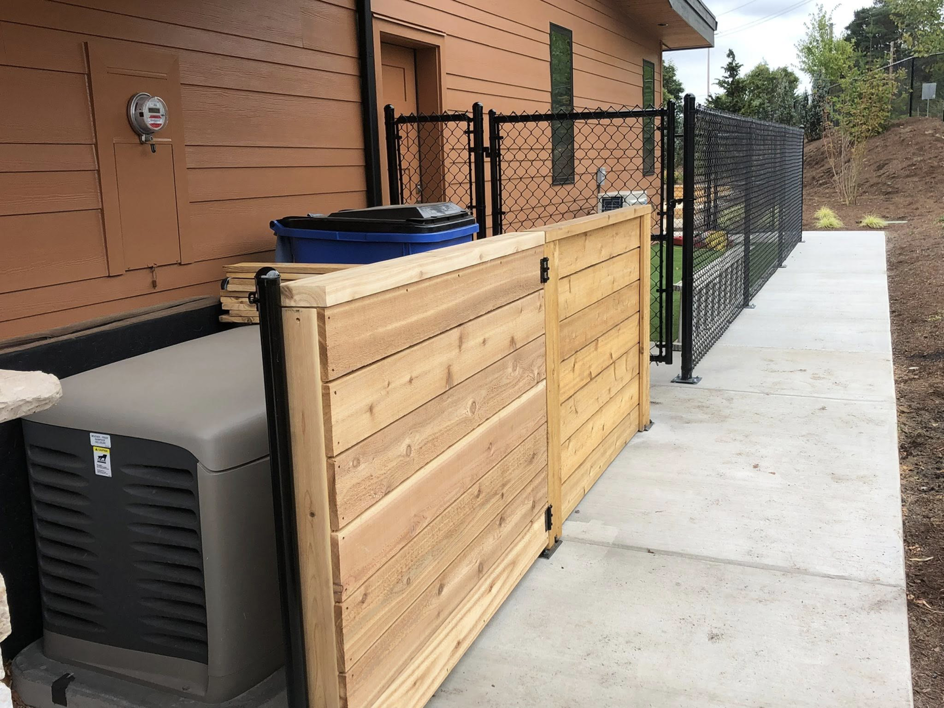 A newly installed wooden privacy fence section next to an outdoor generator by J & M Fence Co. in Vancouver, WA.