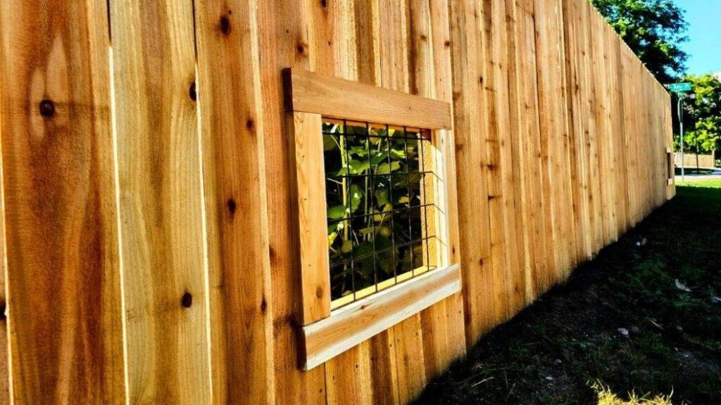 A custom wooden privacy fence featuring a small window, installed by GreenView Solutions in Denver, CO.