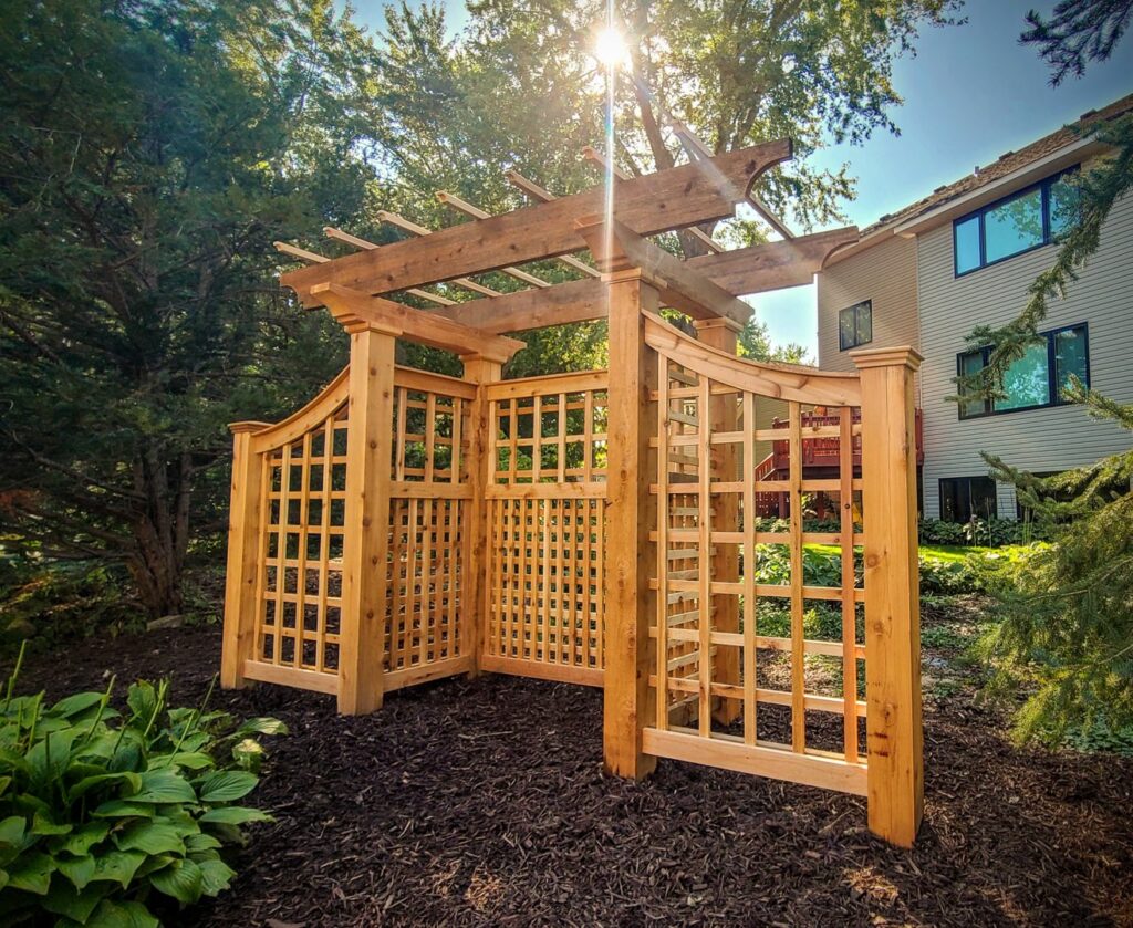 A custom wooden privacy screen and trellis structure in a garden, built by Minnesota Pergolas in Lakeland, MN.