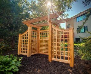 A custom wooden privacy screen and trellis structure in a garden, built by Minnesota Pergolas in Lakeland, MN.