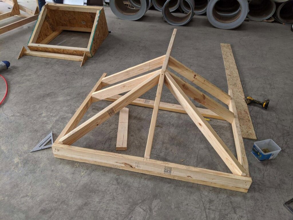 A wooden roof truss being assembled on a concrete floor, showing construction work by Austin Roofing and Construction in Austin, TX.