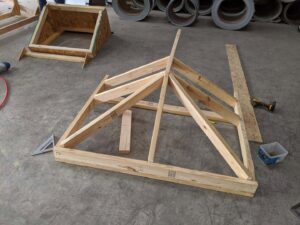 A wooden roof truss being assembled on a concrete floor, showing construction work by Austin Roofing and Construction in Austin, TX.