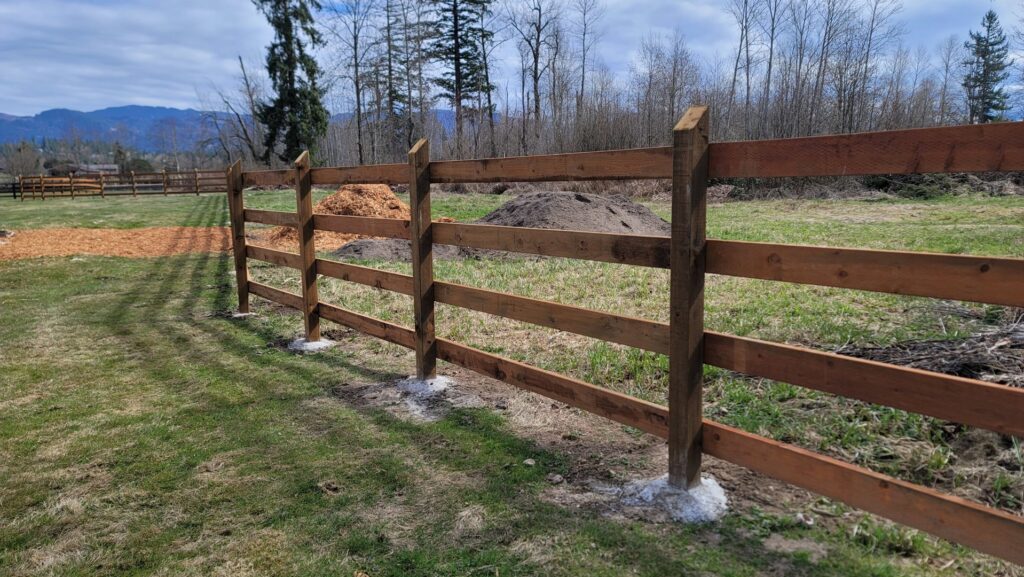 A newly installed wooden split-rail fence in a rural setting by LMS Landscapes & Fence services in Auburn, WA.