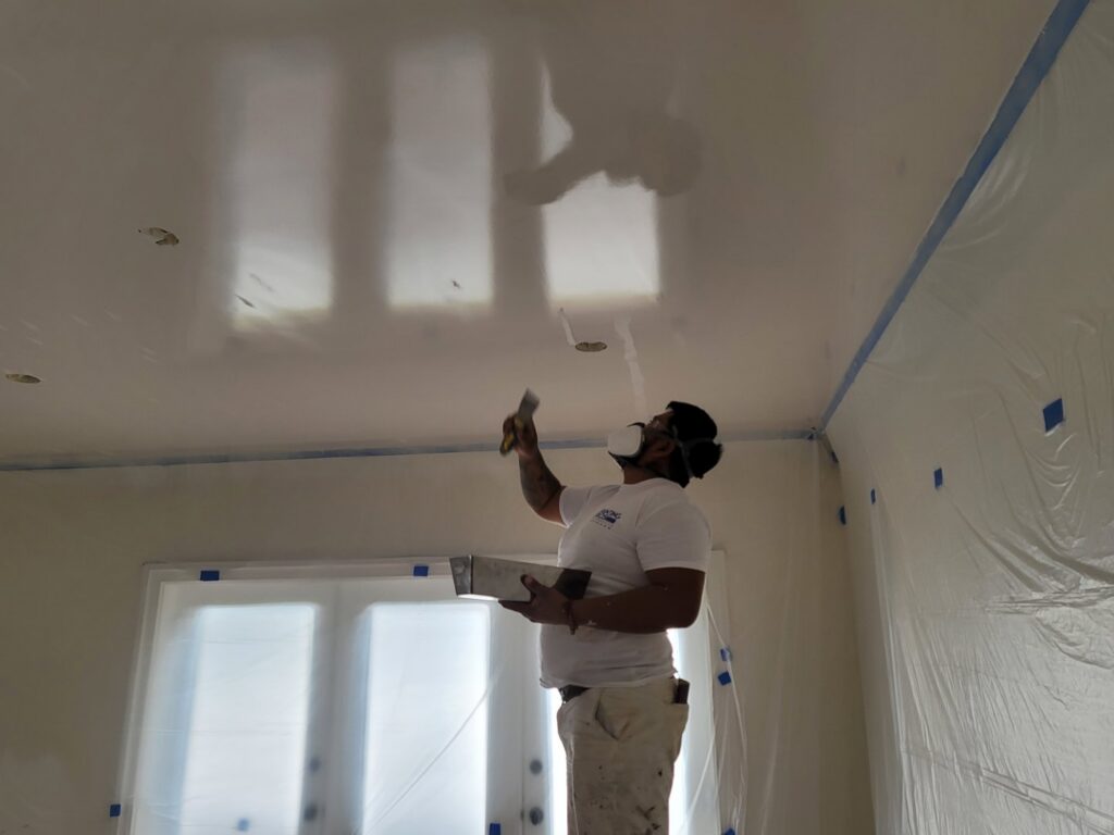 A skilled worker applying compound to a ceiling, with the room prepped, by Painting Pros of Knoxville in Knoxville, TN.