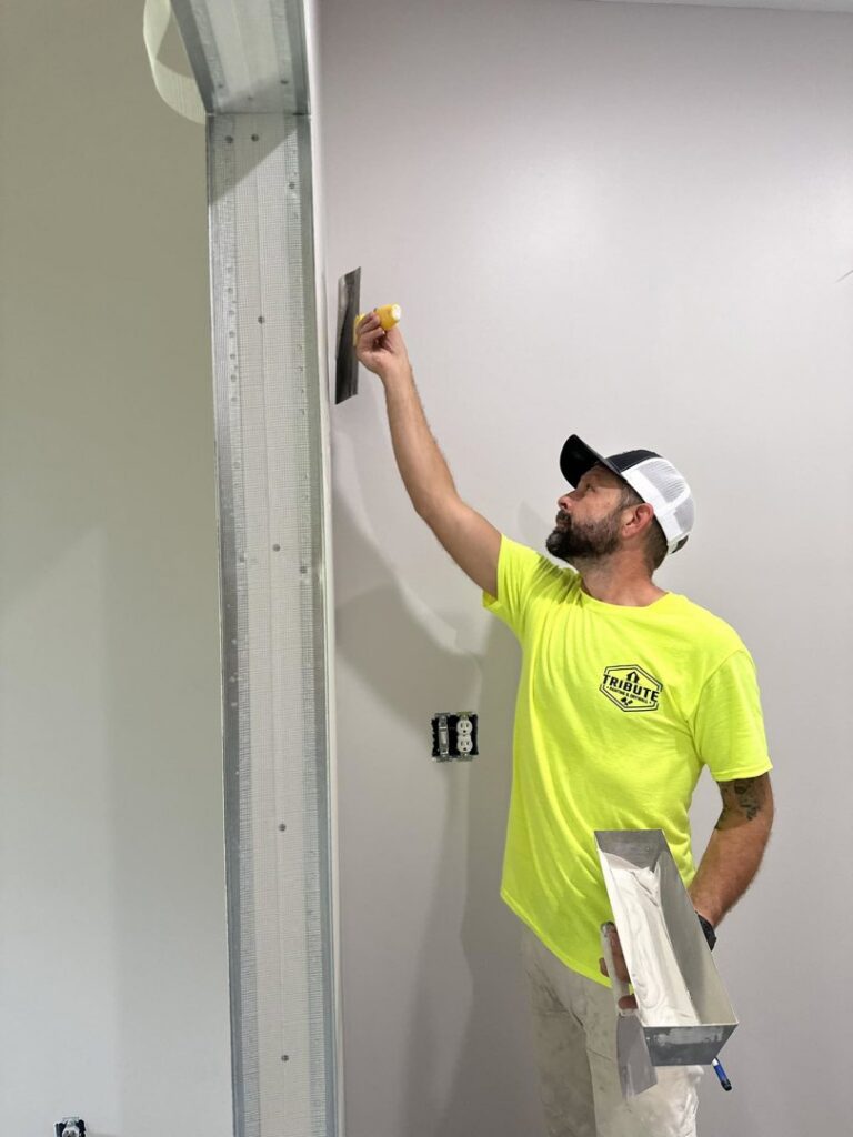 A skilled worker from Tribute Painting & Drywall applying drywall compound to a wall in St. Louis, MO.