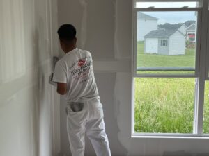 A worker applying drywall mud to a wall, performing finishing work for Hahn Brothers Drywall Co Inc in Evansville, IN