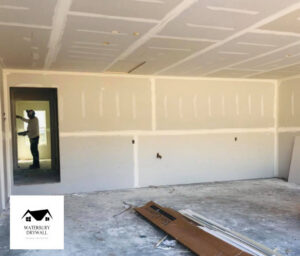 A worker applying drywall mud to taped seams in a room, showcasing finishing work by Waterbury Drywall in Waterbury, CT.