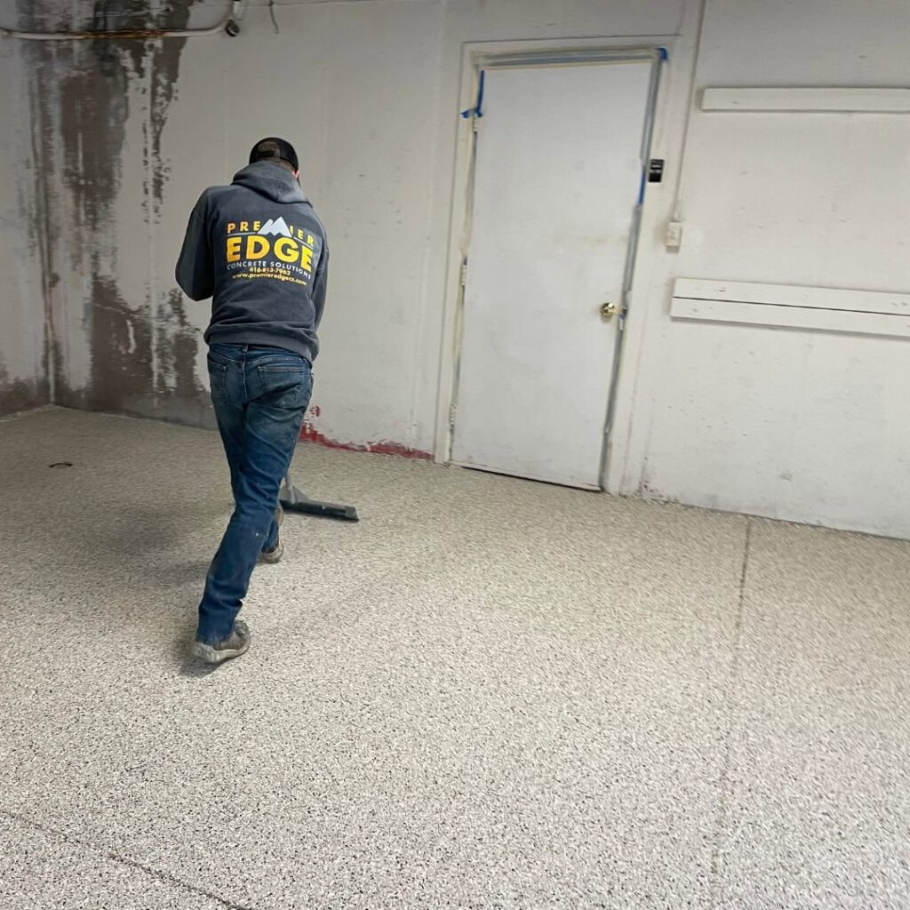 A worker applying an epoxy floor coating for Premier Edge Concrete in Grand Rapids, MI