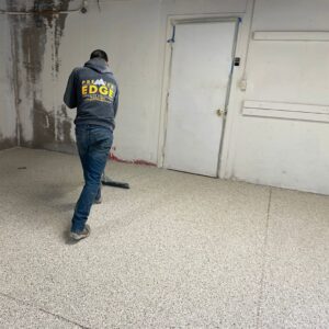 A worker applying an epoxy floor coating for Premier Edge Concrete in Grand Rapids, MI