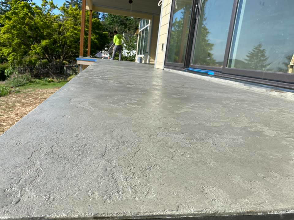 A worker applying a durable textured exterior coating, a service provided by Titan Exteriors in Hillsboro, OR.