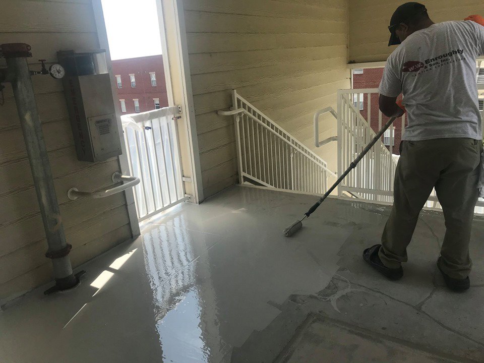 A worker applying a protective floor coating with a roller for WW Enroughty & Son, Inc. in Richmond, VA.