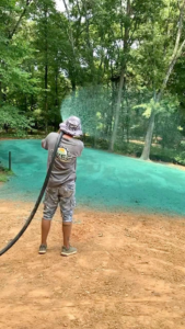 A worker actively applying hydroseed to a sloped area for erosion control by Tennessee Valley Erosion Control in Huntsville, AL.
