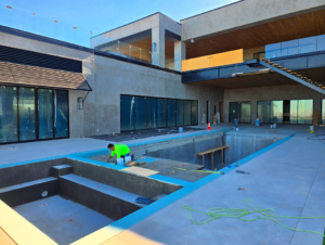A worker applying sealant to a pool edge during construction by Premier Paradise, Inc. in Gilbert, AZ.