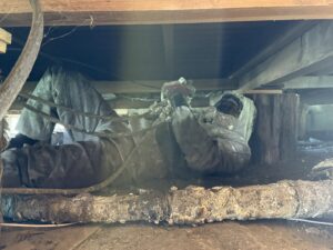 Worker in protective gear applying spray foam insulation in a crawl space for IFOAM Insulation of Hill Country in San Antonio, TX