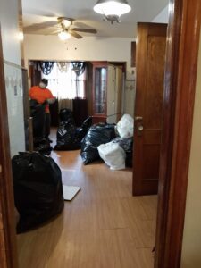 A worker bagging junk for removal in a room, demonstrating services by In & Out Junk Removal Service LLC in Chicago, IL.