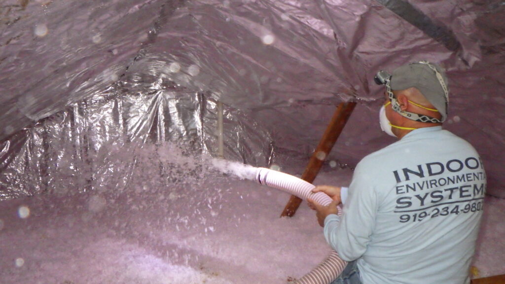 A worker blowing insulation into an attic during an installation service by Indoor Environmental Systems in Cary, NC.