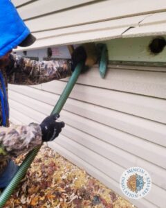 A worker blowing insulation into an exterior wall cavity of a house by Mincin Insulation Service Inc. in Pittsburgh, PA.