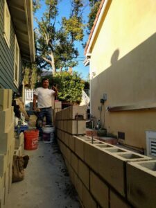 A worker building a concrete block retaining wall, a masonry project by Juancho's Handyman in Salida, CO.