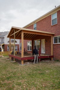 A worker constructing a screened porch and deck structure for a client of Vision Construction in Framingham, MA.