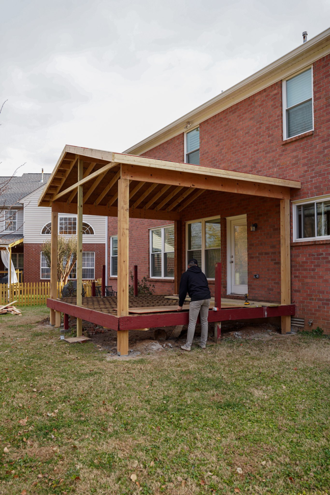 A worker constructing a screened porch and deck structure for a client of Vision Construction in Framingham, MA.