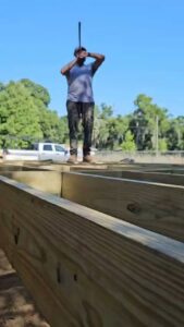 A worker constructing a wooden deck frame, part of a project by Alejandro Melo Contractor corp in Tampa, FL.