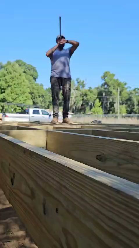 A worker constructing a wooden deck frame, part of a project by Alejandro Melo Contractor corp in Tampa, FL.