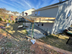 A worker on a ladder constructing a wooden patio cover for a home by A.G Deck & Painting in Charlotte, NC.