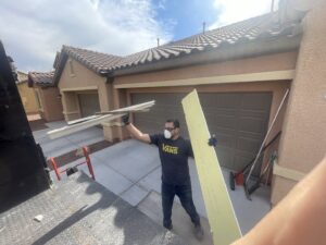 A Tidy Toss worker carrying long pieces of construction debris towards a junk removal truck in Las Vegas, NV