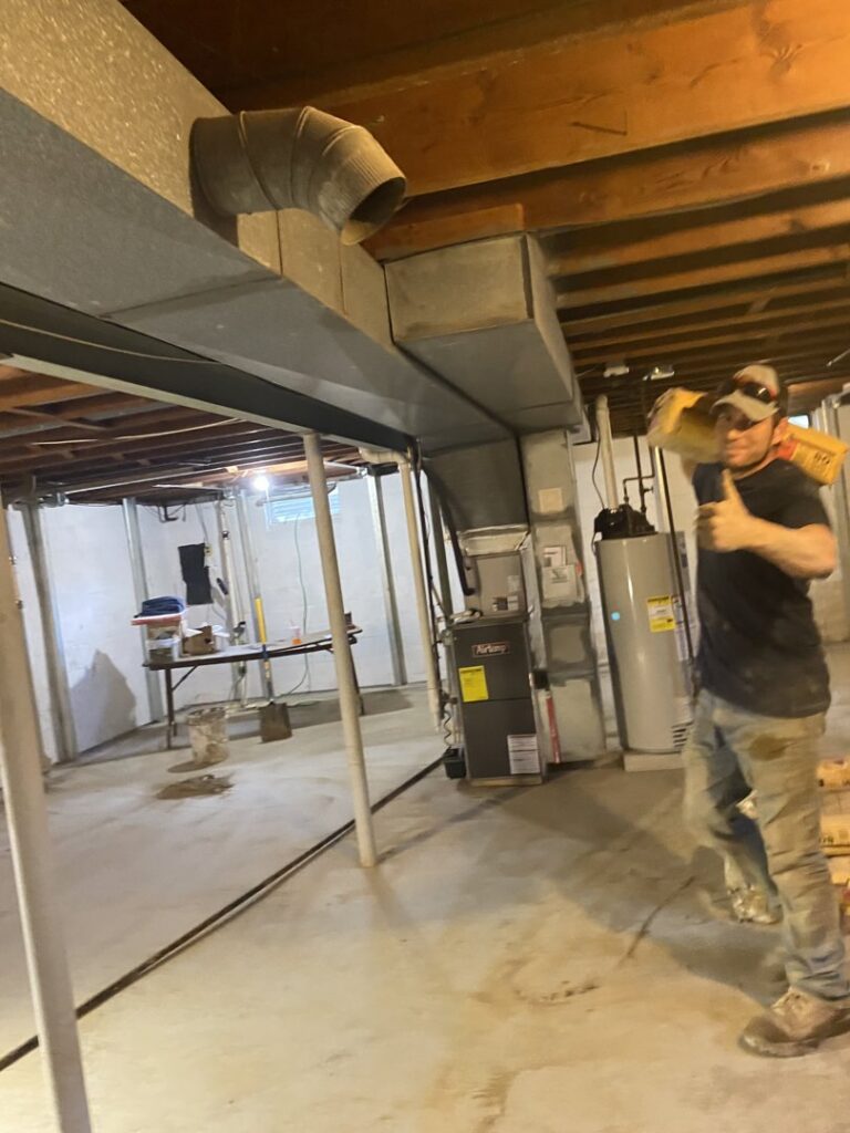 A worker carrying construction materials in a basement for Woodford Bros., Inc. in Apulia Station, NY
