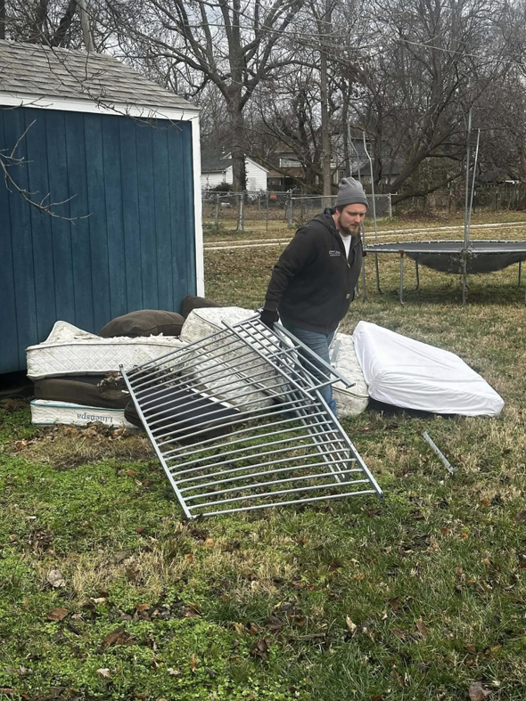 A worker carrying a metal frame as part of a junk removal job for Tornado Alley Junk Removal & Trash in Springfield, MO.