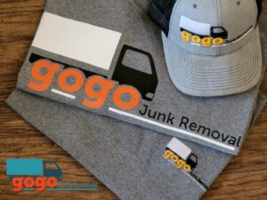 A GoGo Junk Removal worker cleaning a very messy room filled with trash and debris in Atlanta, GA.