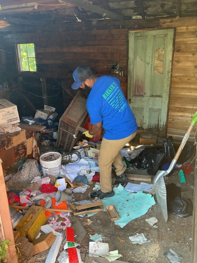A worker from Barkers Junk Removal & Hauling LLC clearing a cluttered room, removing items in Roanoke, VA.