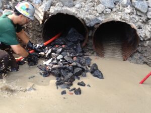 A worker clearing rocks and debris from a culvert pipe for Precision Industrial Maintenance, Inc. in Schenectady, NY.