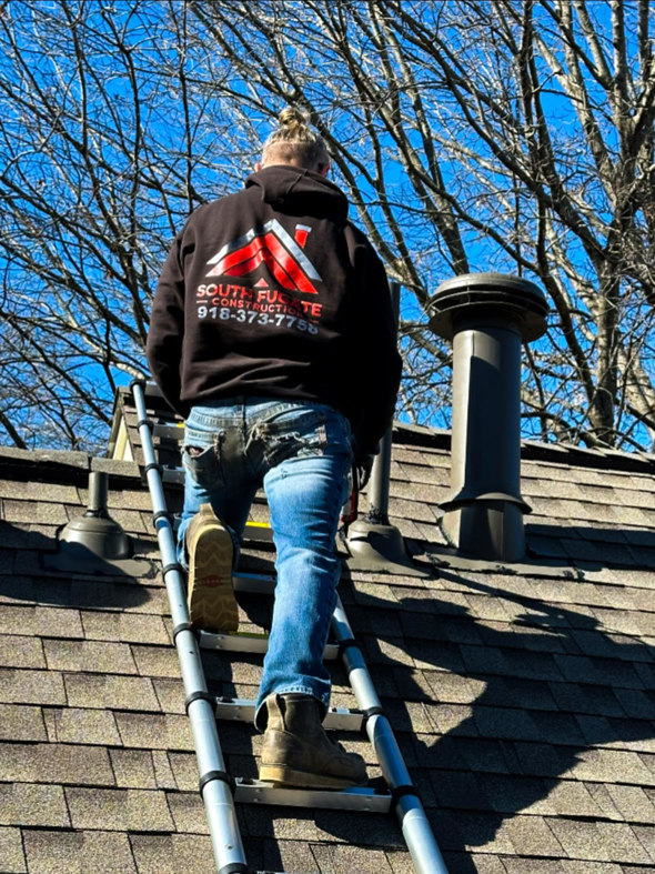 A worker from South Fugate Construction LLC climbing a ladder onto a roof for a handyman job in Tulsa, OK.
