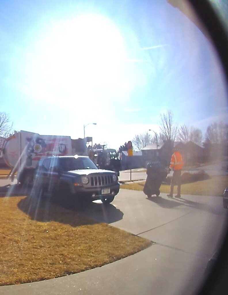 A worker collecting a trash can near an Abe's Trash Service, Inc. truck in Omaha, NE.