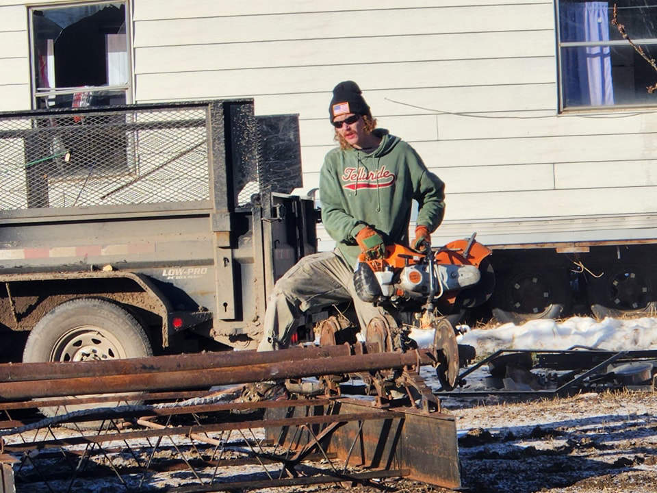A worker cutting scrap metal with a large saw, performing junk removal services for 701 Scrap in Williston, ND.