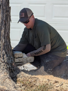 A tree service worker using a chainsaw to cut a tree trunk, with sawdust flying, performed by Affordable Tree Service LLC in Saint Charles, MO.