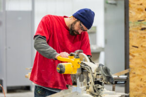 A skilled worker using a miter saw to cut wood for construction, performed by Comforts of Home Services Inc in Aurora, IL