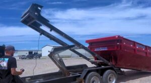A worker from Jedi Junk Removal Garbage Services Pocatello, ID, operating a remote to deliver a roll-off dumpster.