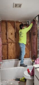 A worker demolishing a bathroom shower wall during a renovation project by Castillejo Handyman Services in San Diego, CA