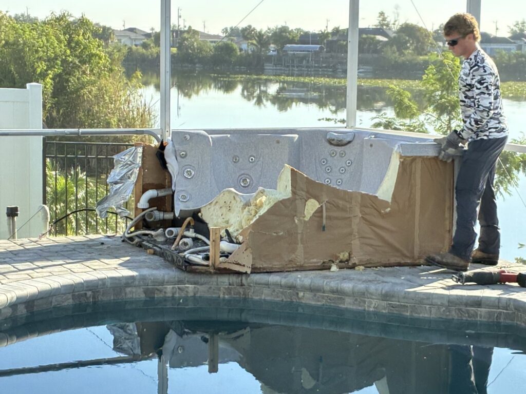 A worker dismantling a hot tub next to a swimming pool for Anthony's Junk Removal & Delivery LLC in Cape Coral, FL.