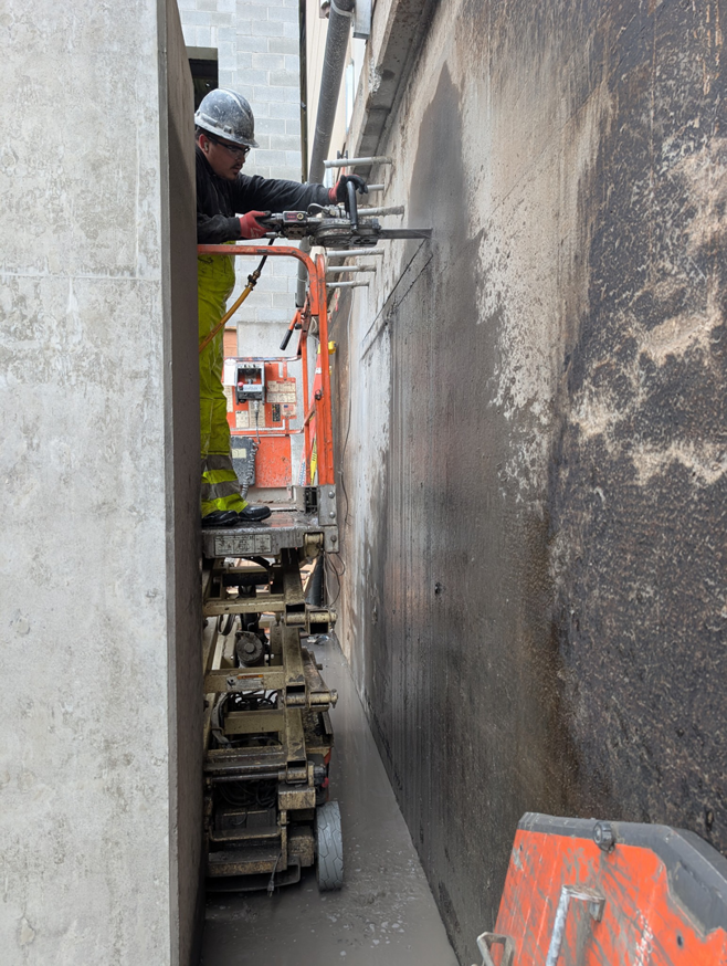 A worker on a lift using a specialized machine to drill into a concrete wall for Interstate Sawing & Drilling in Yakima, WA.