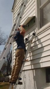 A worker drilling into exterior siding, performing a handyman service for ADDICT INSULATION, LLC in St. Charles, MO.