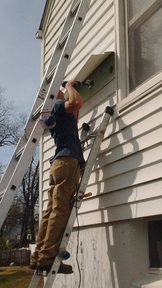 A worker drilling into exterior siding, performing a handyman service for ADDICT INSULATION, LLC in St. Charles, MO.
