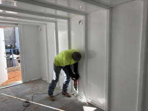 A worker drilling into the interior wall of a newly installed storm shelter by Enid Storm Shelters in Enid, OK.
